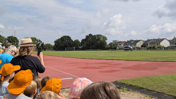 Einige Kinder mit orangefarbenen Mützen beobachten eine Hubschrauberlanund Einige Kinder mit orangefarbenen Mützen beobachten eine Hubschrauberlanund